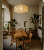 Lotus petal pendant light hanging above wooden dining table with natural decor