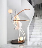 Illuminated dancer sculpture floor lamp with glowing spheres in a luxury modern interior near marble staircase