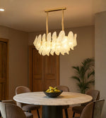 Frosted glass petal dining chandelier with warm light above a marble dining table in a modern interior