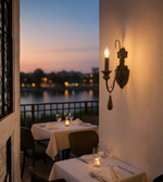 Vintage candle-style wall sconce illuminating a romantic outdoor dining area at sunset
