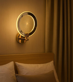 Golden infinity halo wall light with spiral LED effect mounted above bed