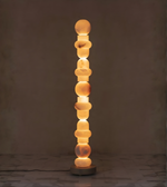 Vertical marble floor lamp with stacked stone design against dark background
