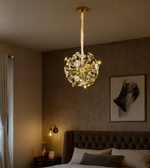 Solis Orb gold chandelier resembling sunburst design in a modern bedroom.
