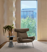Modern brown leather accent chair and striped side table in a bright, contemporary living room