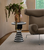 Modern striped accent table with a potted plant beside a brown armchair in a stylish living room