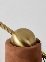 Detail view of brass joint and textured tan base of floor lamp