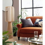 Wooden floor lamp with vertical slats beside modern sofa