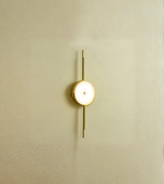 Modern circular wall sconce with black metal frame on textured wall