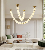 Modern living room with a large chandelier, sofa, and coffee table.