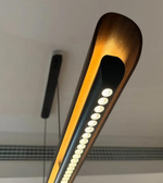 Wooden slim linear LED pendant light by Daya Worldwide hanging from ceiling, modern design with warm wood finish.