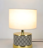 Table lamp with white shade and patterned base on a neutral background