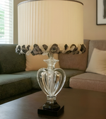 Decorative lamp with crystal base and floral design on a table in a living room.