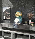 Decorative astronaut figure holding a light bulb on a shelf with a marble wall background.