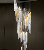 Modern chandelier with glass panels and gold accents against a dark background