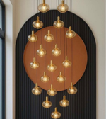 Modern chandelier with multiple hanging lights against a decorative wall.