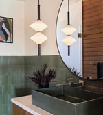 Bathroom interior with green tiles, a round mirror, and pendant lights.