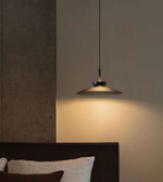 Modern pendant light hanging above a bed in a bedroom setting