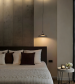 Modern bedroom with a bed, side table, and pendant light.