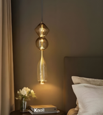 Modern pendant light fixture in a bedroom setting with 'Knoll' book and flowers.