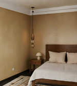 Bedroom with wooden bed, beige walls, and pendant light fixture.