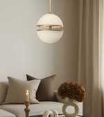 Modern pendant light hanging above a living room with a sofa and decorative items.