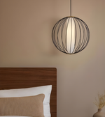 Modern pendant light fixture hanging above a bed in a bedroom setting.