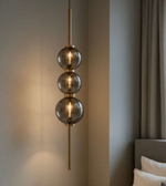 Modern pendant light with three glass shades in a room setting.