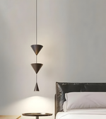 Modern pendant light fixture hanging above a bed in a bedroom setting.