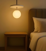 Bedroom with a bedside table and hanging lamp casting a warm glow.