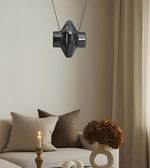 Modern black pendant light hanging above a sofa with decorative pillows and a candle.