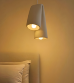 Modern pendant light fixture on a neutral wall with pillows in the foreground