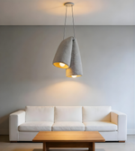 Modern pendant light fixture on a neutral wall with pillows in the foreground