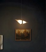 Modern pendant light fixture on a dark wall with a framed painting below.