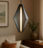 Modern pendant light hanging in a living room with a couch and decorative items.