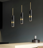 Modern pendant lights with black and gold design hanging against a dark wall.