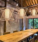 Modern interior with wooden tables and chairs, and three hanging wire pendant lights.
