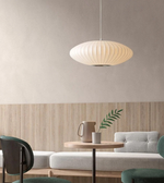 Modern interior with a pendant light, table, and sofa against a neutral wall.