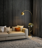 Modern gold arc floor lamp with marble base beside a beige sofa