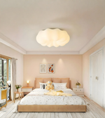 Modern bedroom with a beige bed, ceiling light fixture, and decor elements.