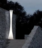 Modern outdoor lamp fixture on a stone wall with trees in the background