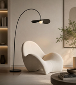 Modern black floor lamp next to a white chair in a stylish room.