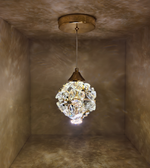 Crystal pendant light hanging from a ceiling in a room with textured walls.