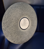 Round stone object with a central circular cutout on a dark blue background
