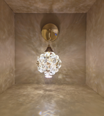 Wall-mounted light fixture with crystal design in a room with beige walls.