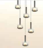 Five modern pendant lights with brushed silver cylindrical shades and frosted glass shades, arranged in a staggered vertical layout against a light beige background.