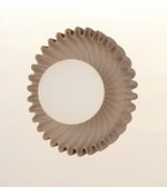 A modern circular ceiling light fixture with a textured, fluted outer rim and a frosted white central globe, shown against a plain off-white background.