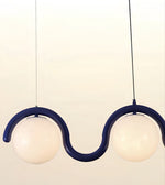 A modern two-light pendant lamp with a curved dark blue frame and frosted white globe shades, suspended against a plain light background.