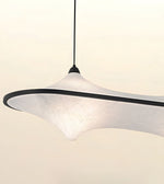 A modern pendant light with a wide, organic-shaped white textured shade and a black rim, suspended by a thin black cord against a warm off-white background.