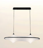A modern pendant light fixture with a wide, curved white shade and a black top bar and suspension cords, shown against a plain light beige background.