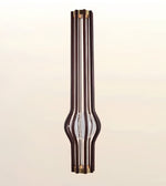 A modern vertical pendant light fixture with multiple dark brown wood-grain rods, brass-toned metal caps, and a clear glass center tube, shown against a soft beige gradient background.